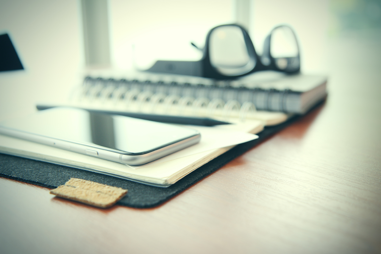 Smart phone close-up,  planning book on wooden desk work space concept